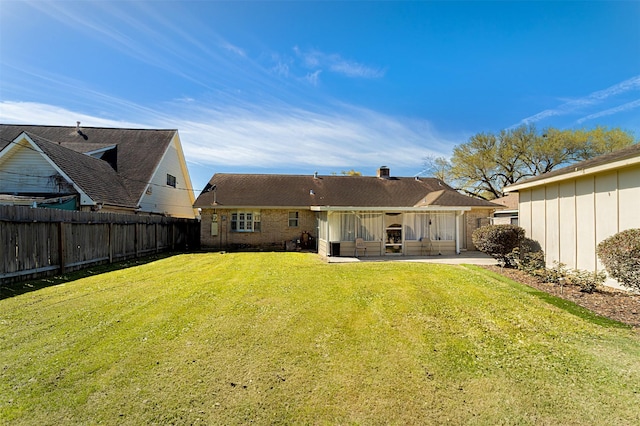 rear view of house featuring a patio, a fenced backyard, a lawn, and a chimney