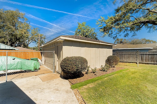 view of side of home featuring a gate, fence, a yard, an outdoor structure, and a garage