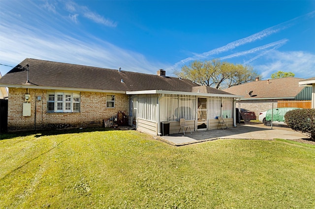 back of property featuring fence, a sunroom, a lawn, a patio area, and brick siding