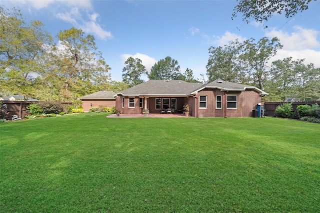 back of property with a patio area, brick siding, a yard, and fence