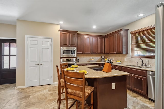 kitchen with a sink, a kitchen bar, backsplash, and stainless steel appliances