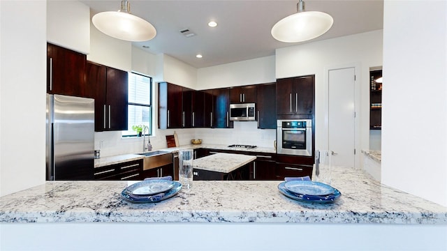 kitchen with a sink, appliances with stainless steel finishes, pendant lighting, tasteful backsplash, and a center island