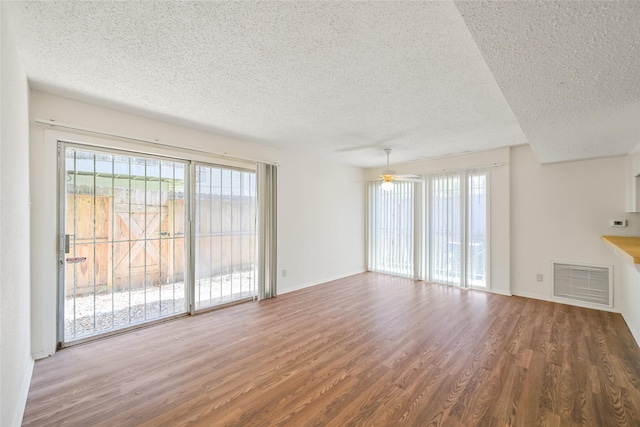 unfurnished living room with ceiling fan, wood finished floors, visible vents, and a textured ceiling