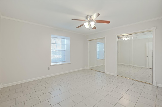 unfurnished bedroom featuring baseboards, crown molding, multiple closets, and a ceiling fan