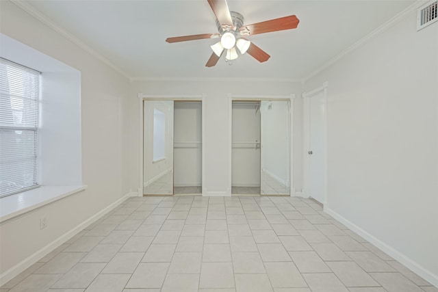 unfurnished bedroom featuring crown molding, visible vents, multiple closets, and baseboards