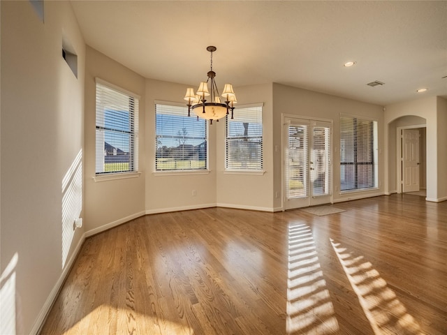 interior space with visible vents, wood finished floors, arched walkways, an inviting chandelier, and baseboards