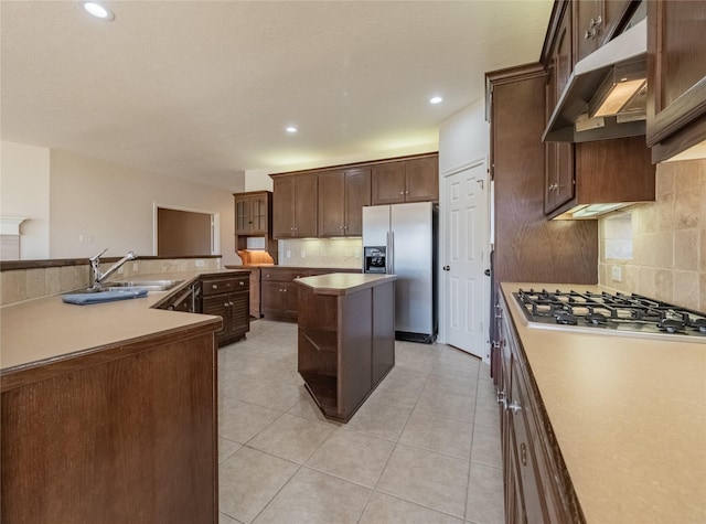 kitchen featuring a sink, under cabinet range hood, appliances with stainless steel finishes, backsplash, and a center island