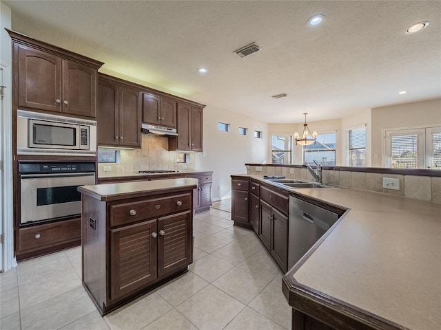 kitchen with visible vents, a sink, decorative backsplash, under cabinet range hood, and appliances with stainless steel finishes