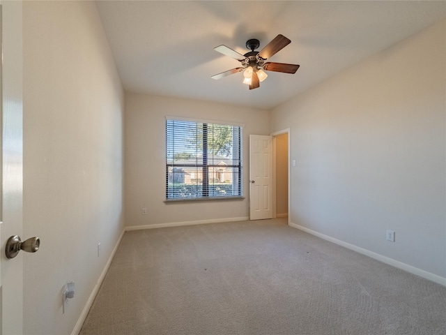 spare room with light colored carpet, baseboards, and ceiling fan