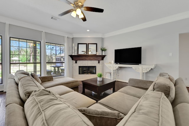 living room with a fireplace, wood finished floors, visible vents, and ornamental molding