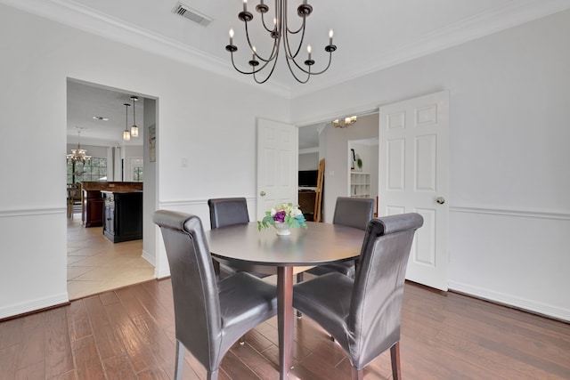 dining room featuring visible vents, wood finished floors, a chandelier, and ornamental molding