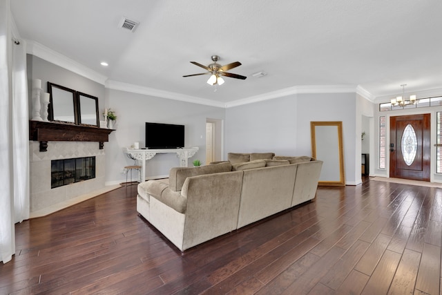 living area featuring dark wood finished floors, visible vents, a fireplace, and ornamental molding