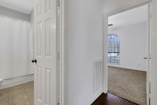 corridor with tile patterned flooring, visible vents, and baseboards