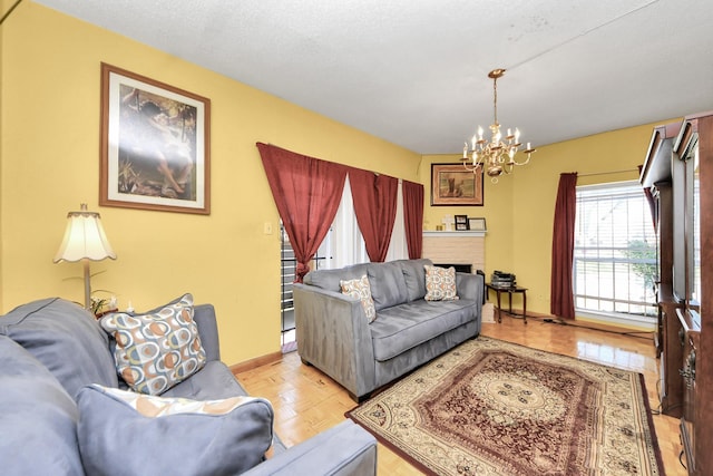 living area featuring baseboards, a brick fireplace, and a chandelier