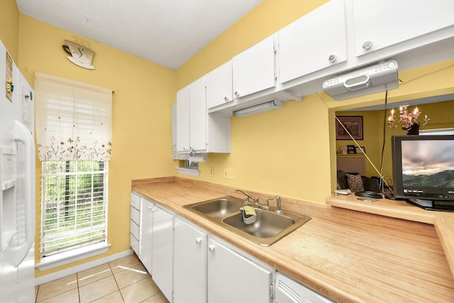 kitchen featuring light tile patterned floors, white cabinetry, light countertops, and a sink