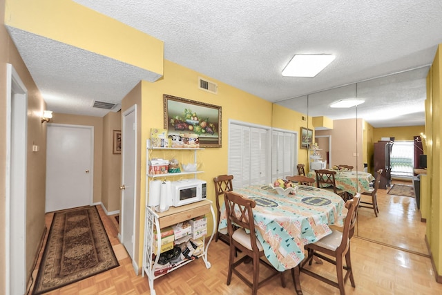 dining room with visible vents, a textured ceiling, and baseboards