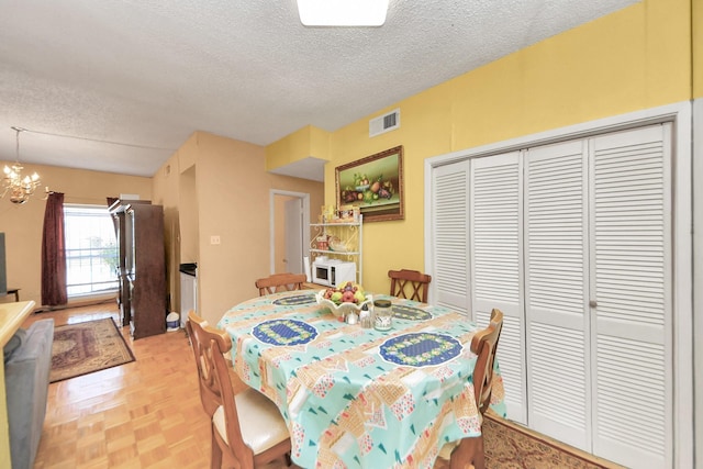 dining room featuring visible vents, a textured ceiling, and a chandelier