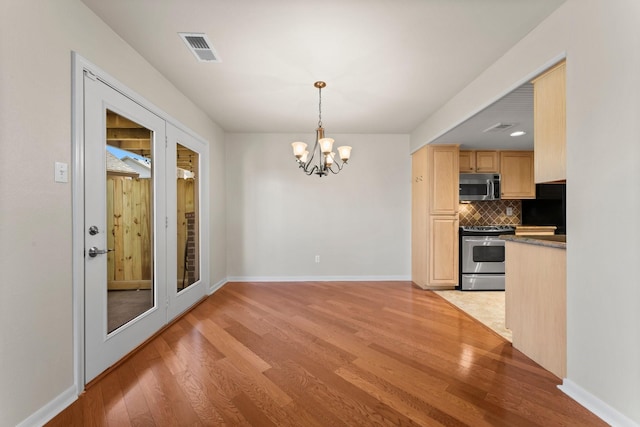 unfurnished dining area with a chandelier, visible vents, light wood-style flooring, and baseboards