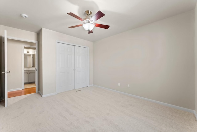 unfurnished bedroom featuring light carpet, ceiling fan, a closet, and baseboards