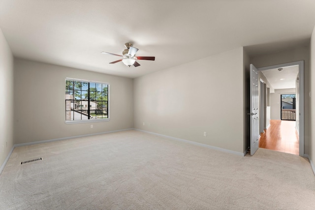 unfurnished room featuring visible vents, light colored carpet, baseboards, and ceiling fan