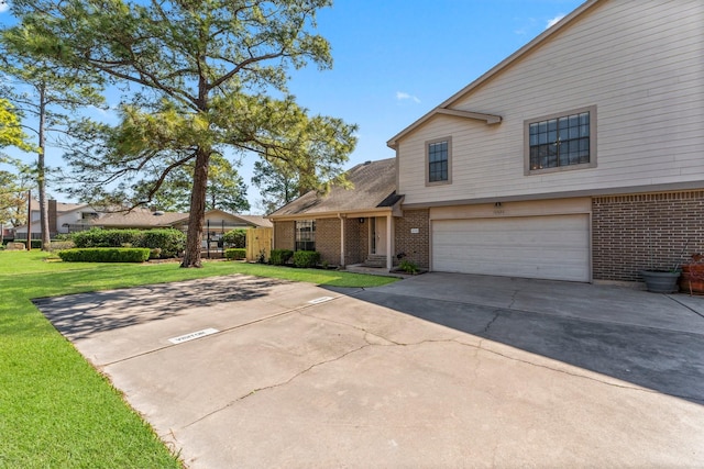 view of front of house featuring brick siding, driveway, an attached garage, and a front yard