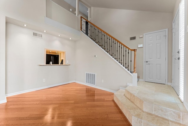 foyer featuring visible vents, stairway, and a towering ceiling