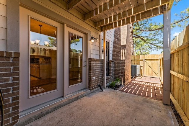 doorway to property with brick siding, fence, central air condition unit, a patio, and a gate