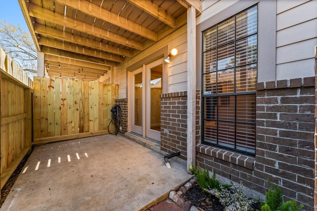 doorway to property featuring a patio, fence, and brick siding