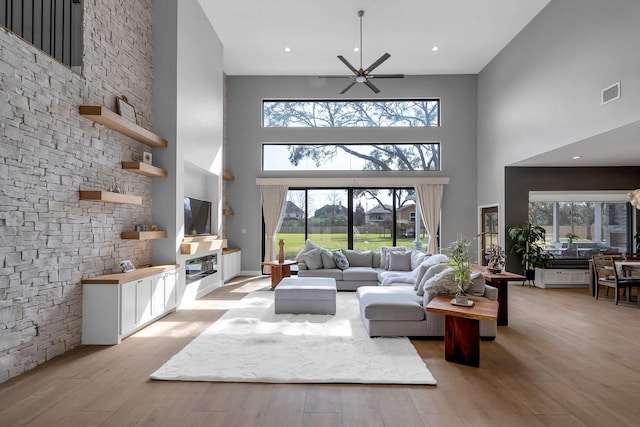 living room with visible vents, light wood-style floors, and a ceiling fan