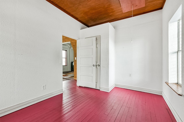 unfurnished room featuring attic access, wood ceiling, baseboards, and wood-type flooring