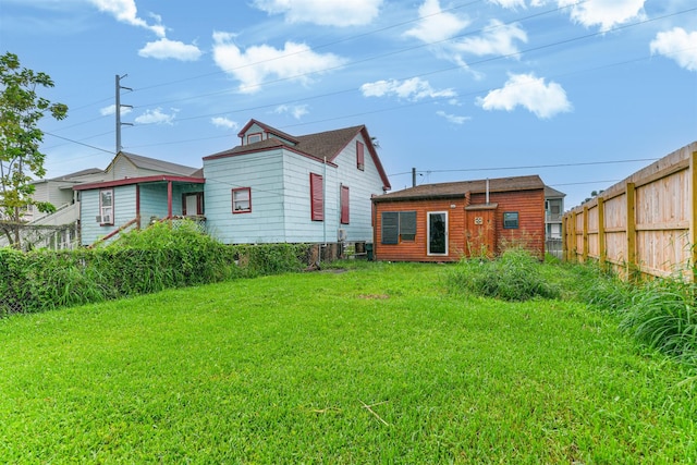 rear view of house with a yard and fence