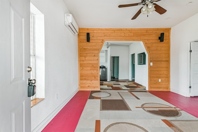 entrance foyer featuring an AC wall unit, wooden walls, baseboards, and ceiling fan