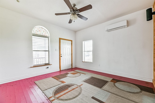 entryway featuring a wall mounted air conditioner, baseboards, hardwood / wood-style floors, and a wealth of natural light