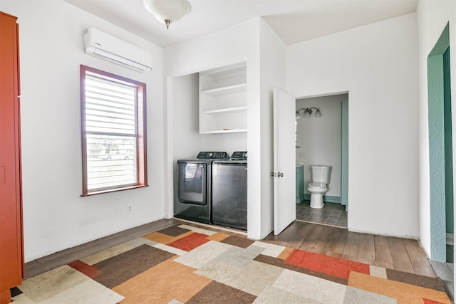 laundry area featuring an AC wall unit, wood finished floors, separate washer and dryer, and laundry area