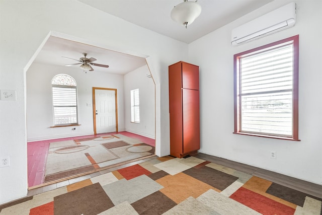 interior space featuring an AC wall unit, baseboards, and ceiling fan