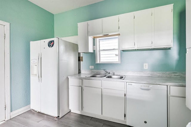 kitchen featuring light wood-type flooring, light countertops, white cabinets, white appliances, and a sink