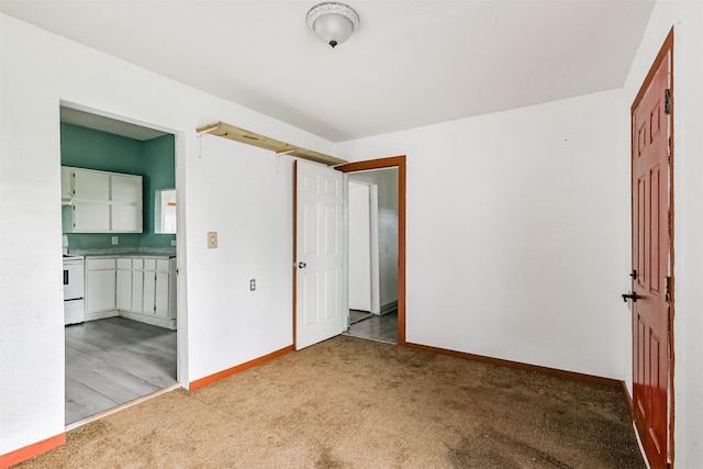 unfurnished bedroom with light colored carpet, ensuite bath, and baseboards