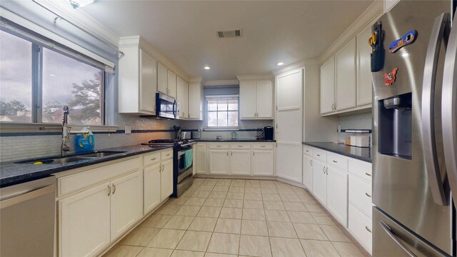 kitchen with dark countertops, tasteful backsplash, appliances with stainless steel finishes, and a sink