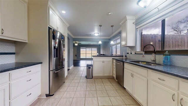 kitchen with crown molding, hanging light fixtures, appliances with stainless steel finishes, light tile patterned flooring, and a sink