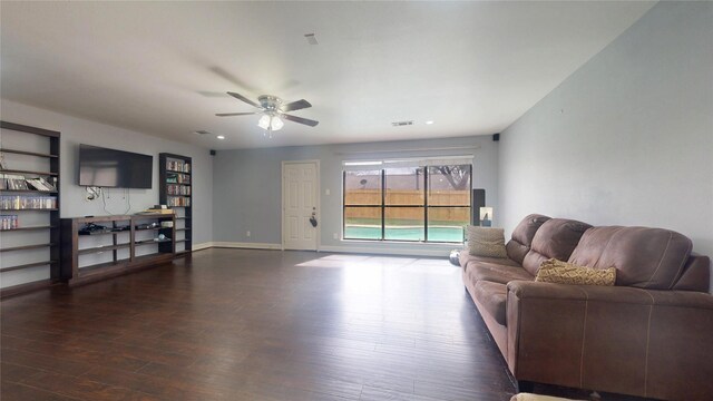 living room featuring visible vents, built in shelves, baseboards, wood finished floors, and a ceiling fan