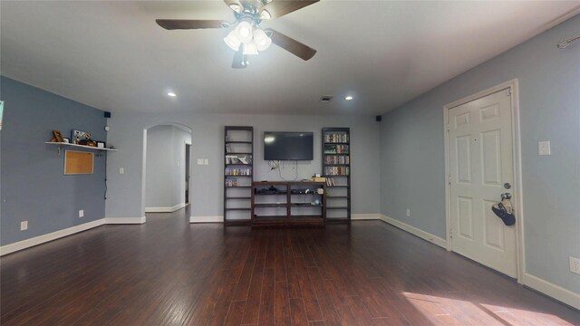 unfurnished living room featuring arched walkways, baseboards, and wood finished floors