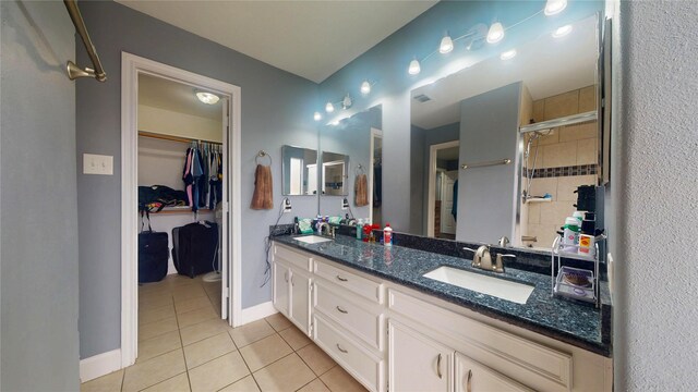 bathroom with tile patterned floors, double vanity, baseboards, and a sink