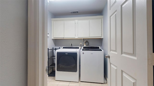 laundry area featuring washer and clothes dryer, visible vents, cabinet space, and light tile patterned flooring