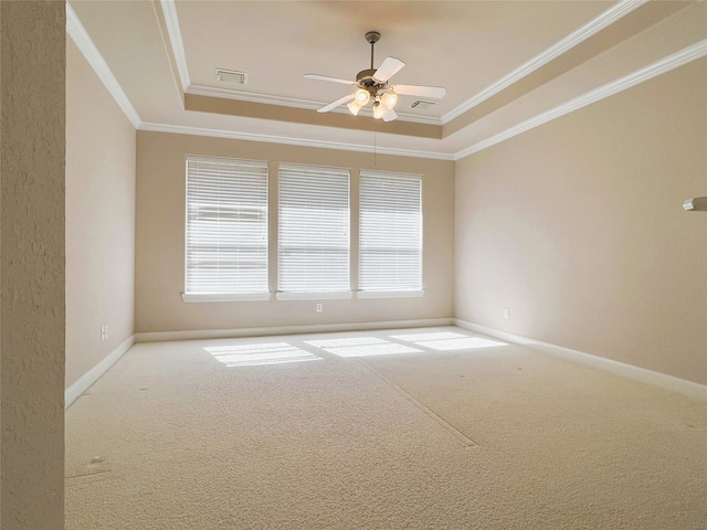 unfurnished room featuring carpet, a tray ceiling, crown molding, and visible vents