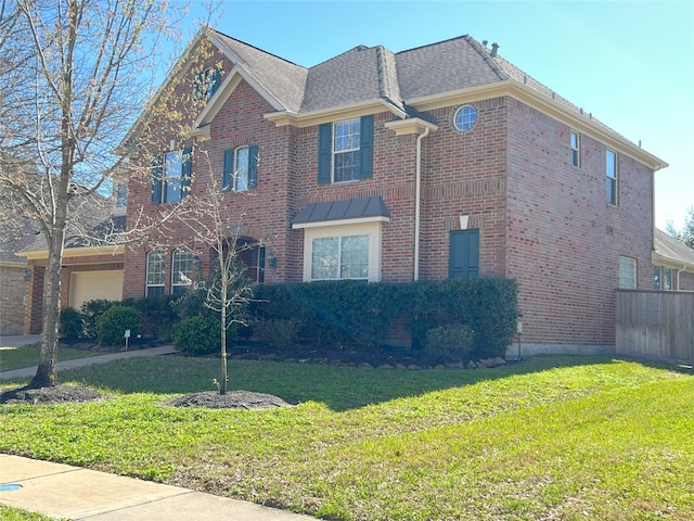 view of front of house with brick siding, an attached garage, a front yard, and fence