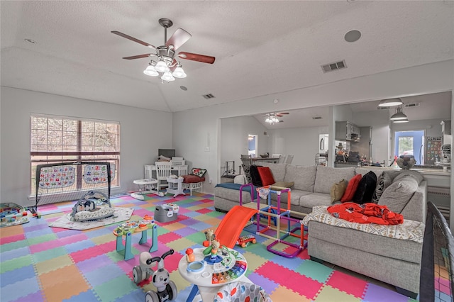 game room with visible vents, a textured ceiling, ceiling fan, and vaulted ceiling