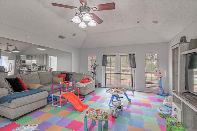 living area with vaulted ceiling, french doors, visible vents, and tile patterned floors