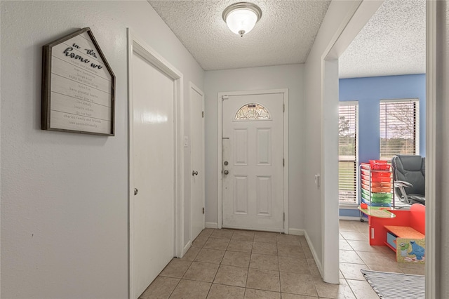 entryway with light tile patterned flooring, a textured ceiling, and baseboards