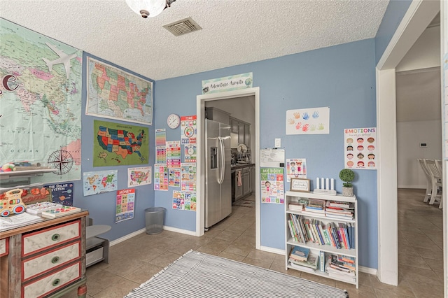 game room featuring tile patterned floors, visible vents, a textured ceiling, and baseboards