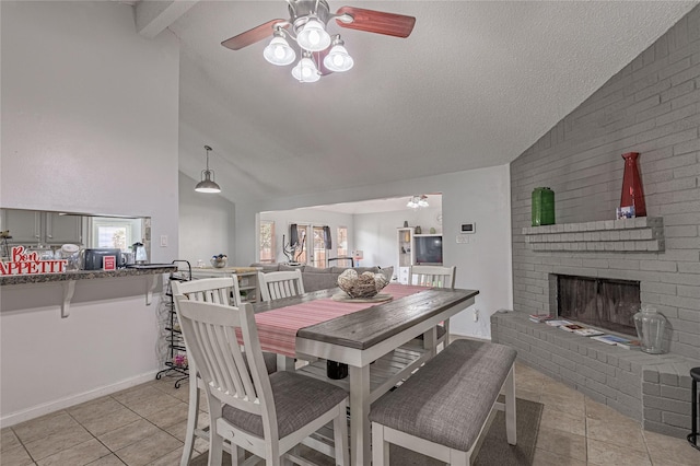 dining room featuring light tile patterned floors, a textured ceiling, a fireplace, and vaulted ceiling